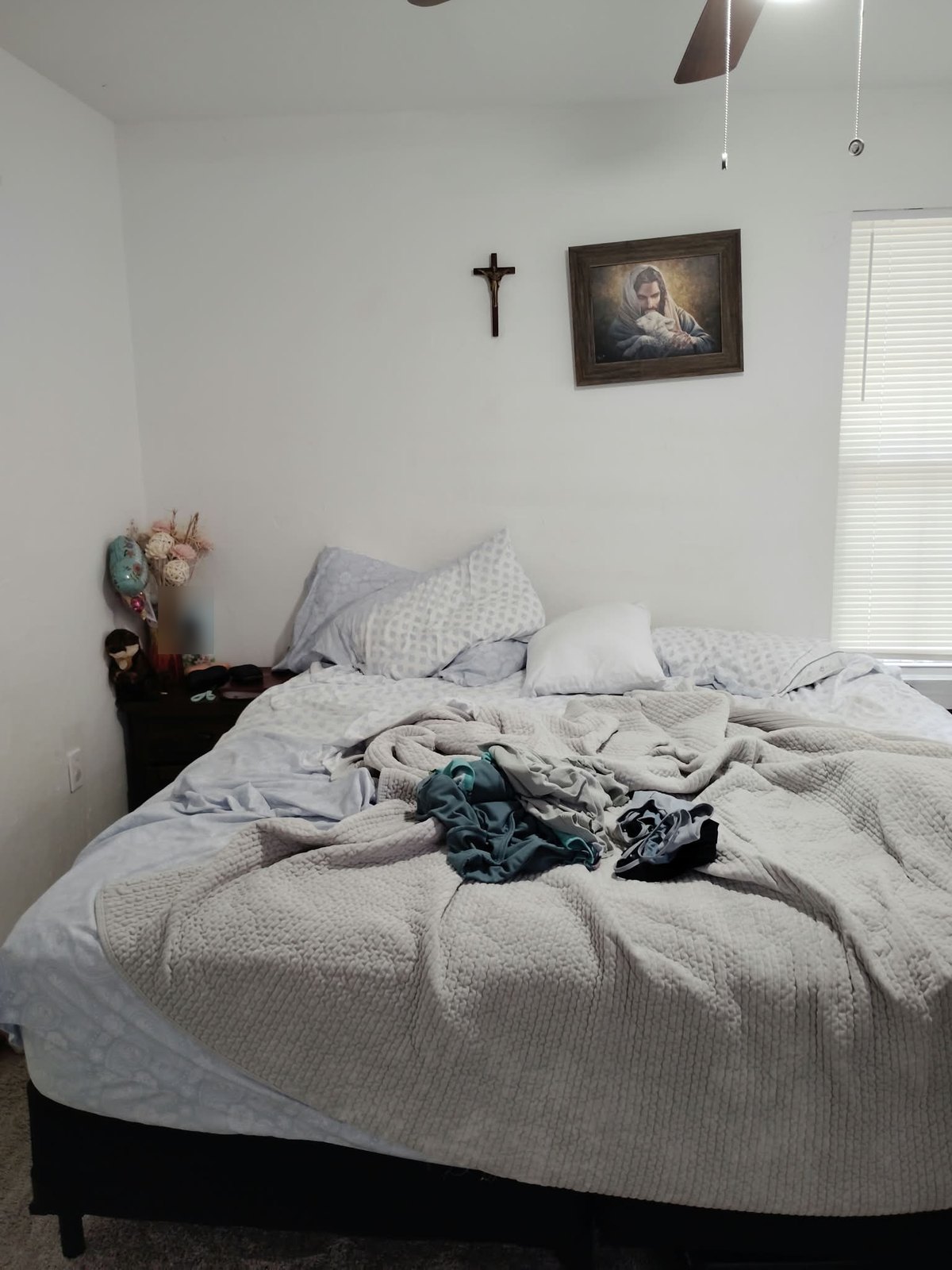 Unmade double bed with laundry piled on it before cleaning