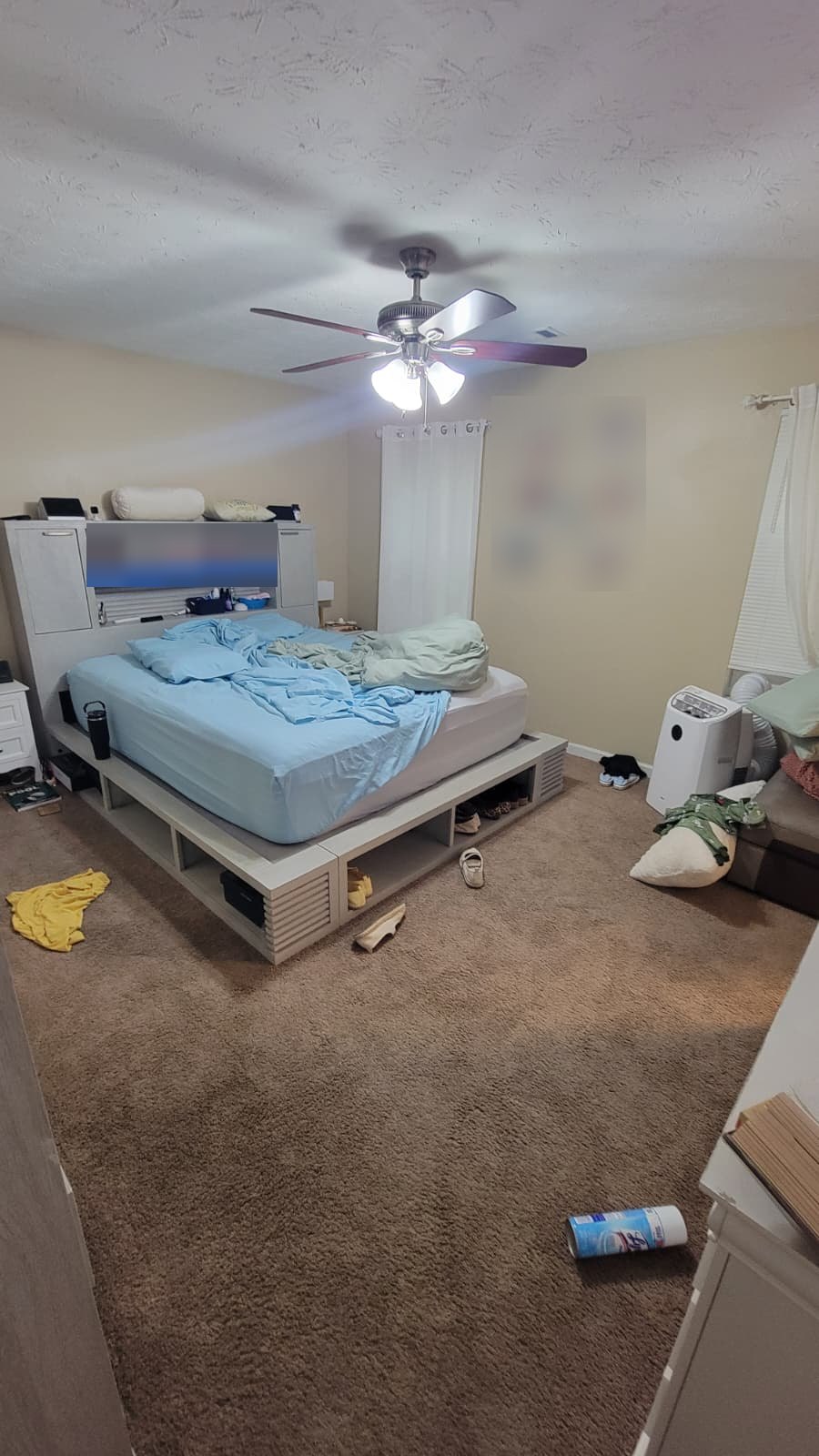 Main bedroom with clothes and clutter across the floor before cleaning